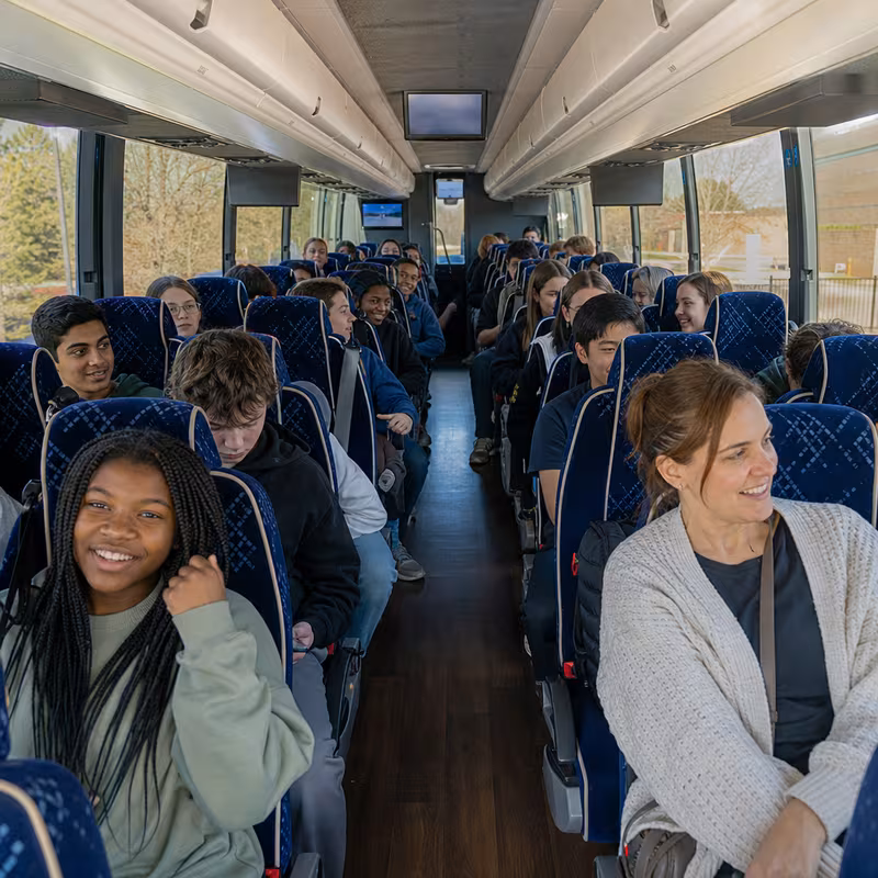 Group boarding a white charter bus for School Transportation transportation in Staten Island